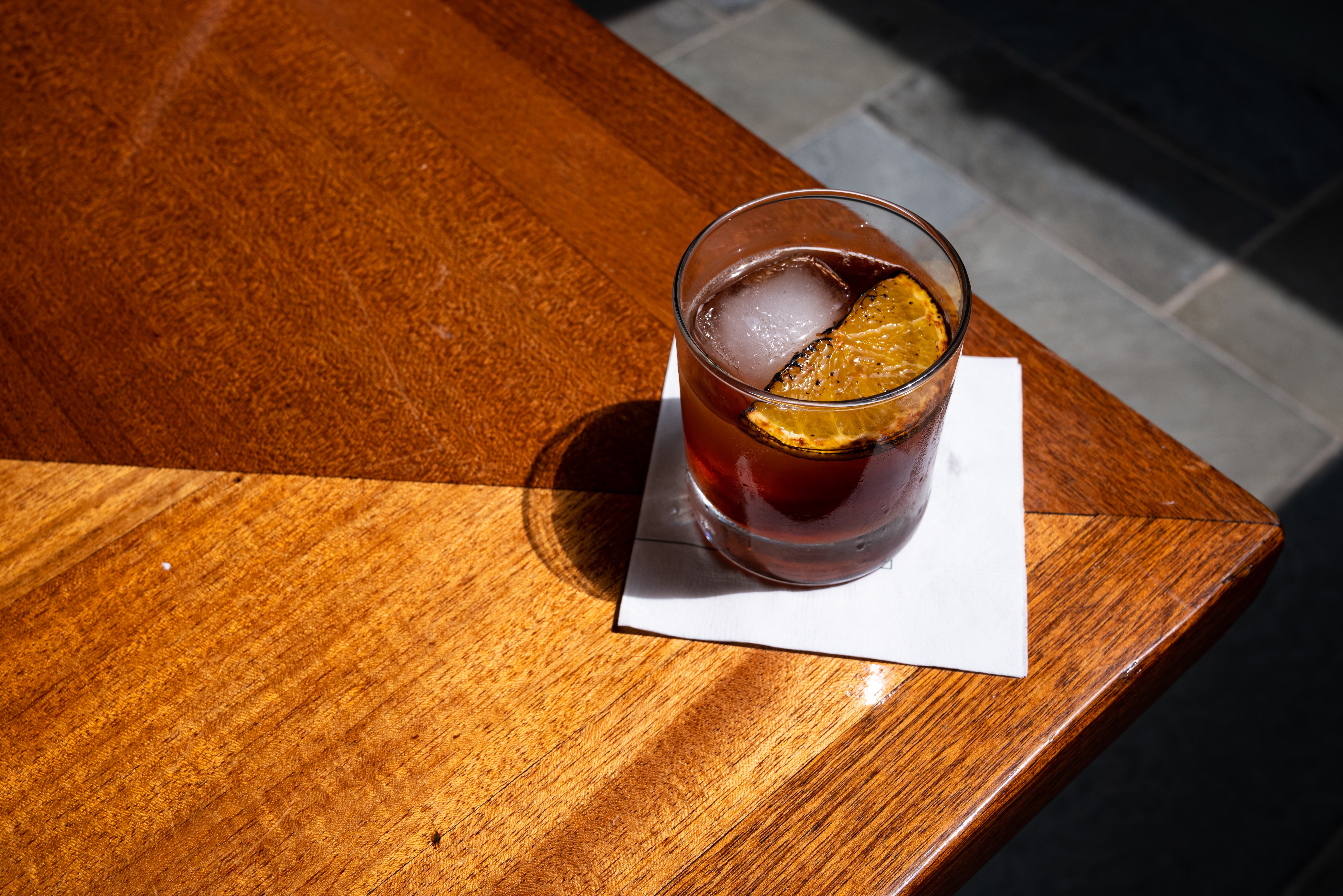 A drink on the edge of a wooden table